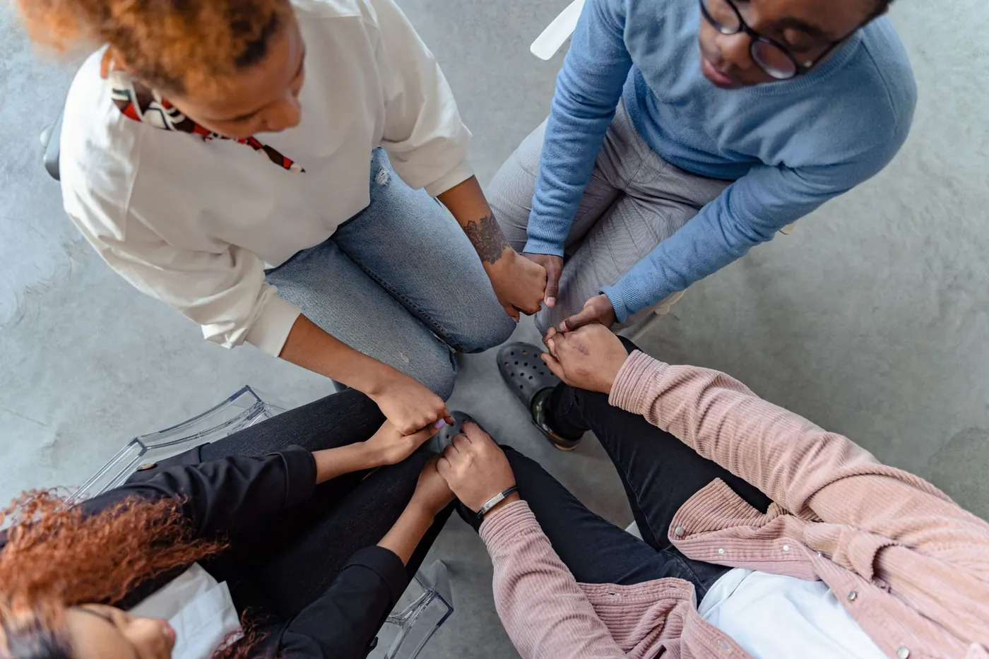 Group members sitting in a circle holding hands in support
